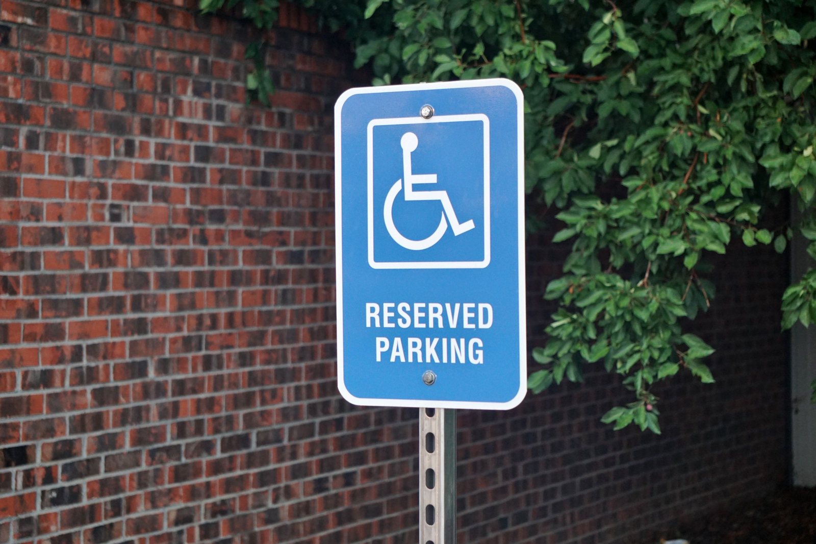 Reserved accessible parking sign mounted on a post beside a building
